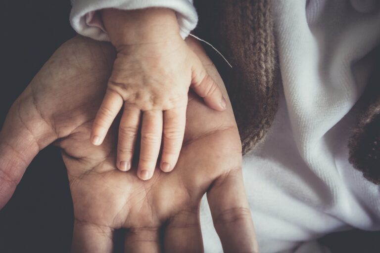 Mano de un bebé encima de la mano adulta