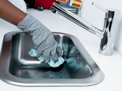 Hay una mano con guantes limpiando un lavaplatos