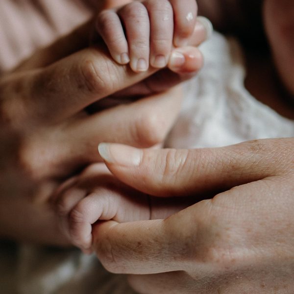 Manos de una mujer y una bebé enlazadas